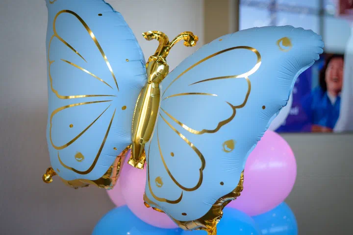 Globo de mariposa azul y dorado sobre globos rosados y azules