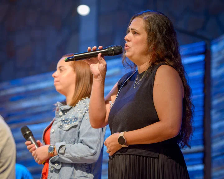 Dos cantantes con micrófono en la tarima