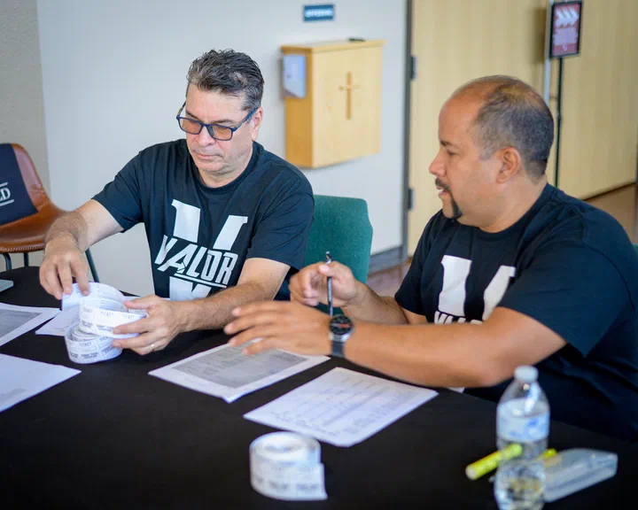 Dos hermanos con camisa de Valor atendiendo la mesa de registro