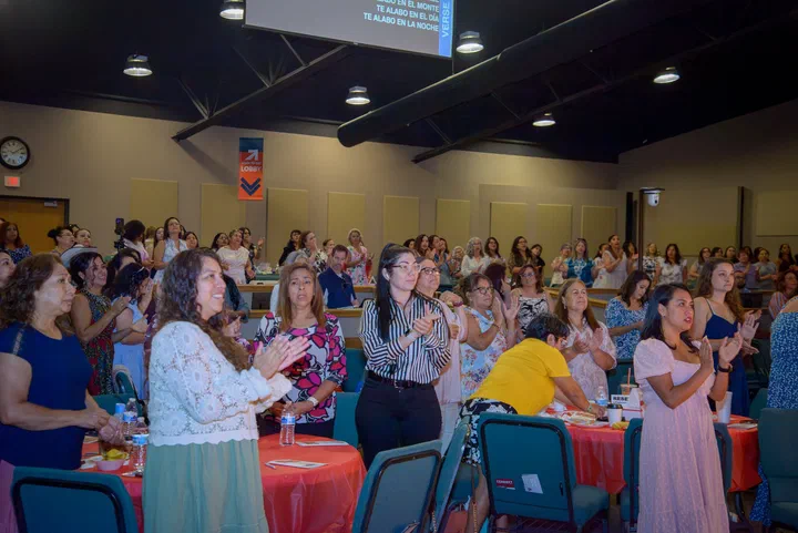 El salón lleno de mujeres de pie en la alabanza