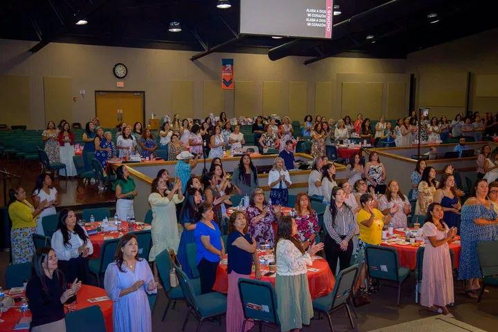 Las mujeres de pie en la alabanza, desde un lado del salón