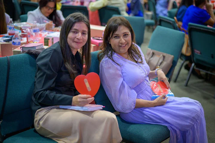 Dos hermanas sentadas, una con un corazón rojo de papel