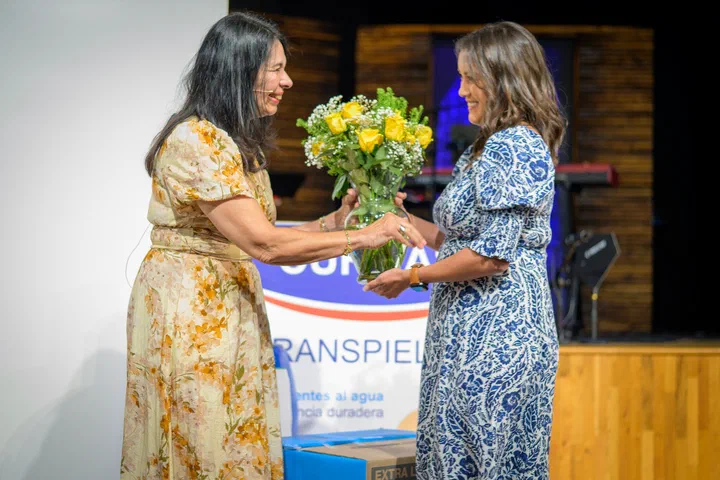 Flor le entrega un ramo de flores amarillas a Yanina Todd