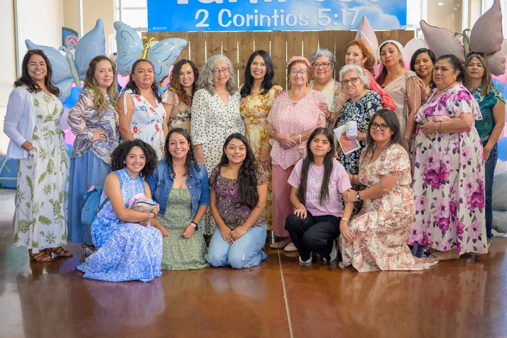 Un grupo grande de hermanas, algunas de rodillas, bajo el letrero del tema