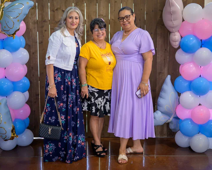Elida con dos hermanas frente a los globos; una de camisa amarilla