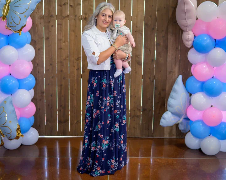 Hermana con un bebé en brazos frente a los globos