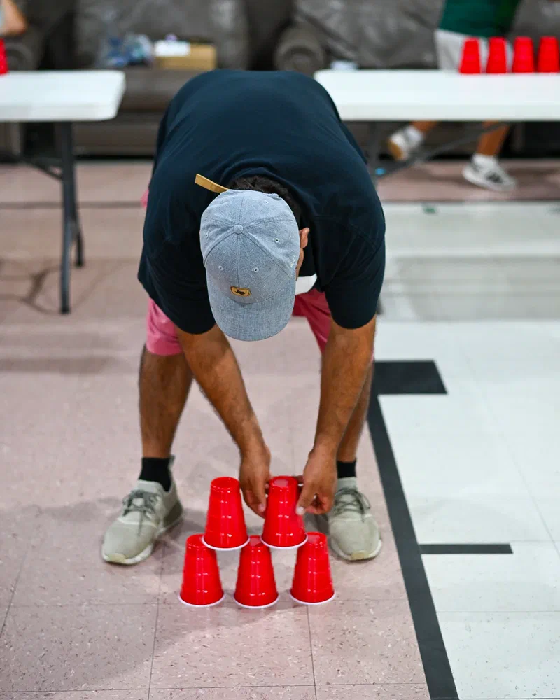 Hermano armando una pirámide de vasos rojos en el piso