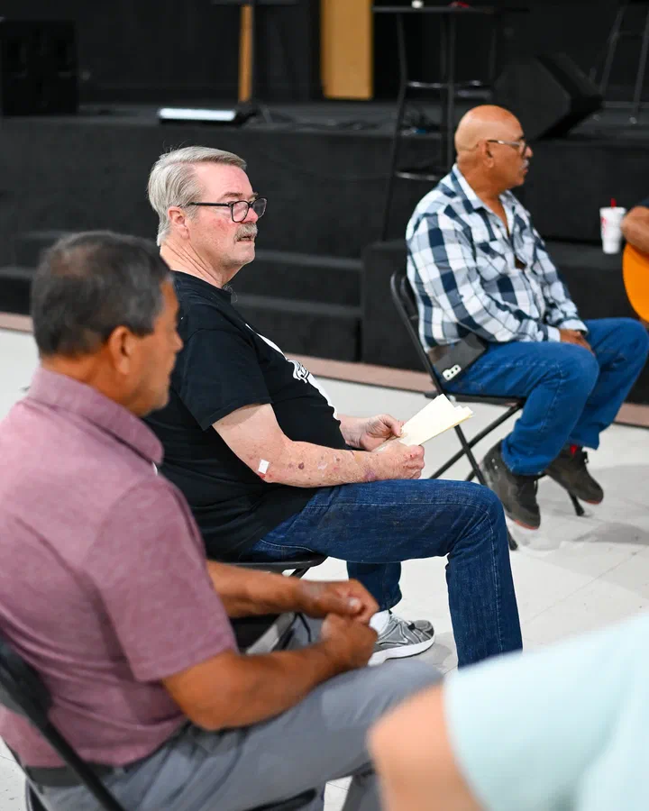 El pastor Rick Todd, con papeles en la mano, escuchando junto a los hermanos