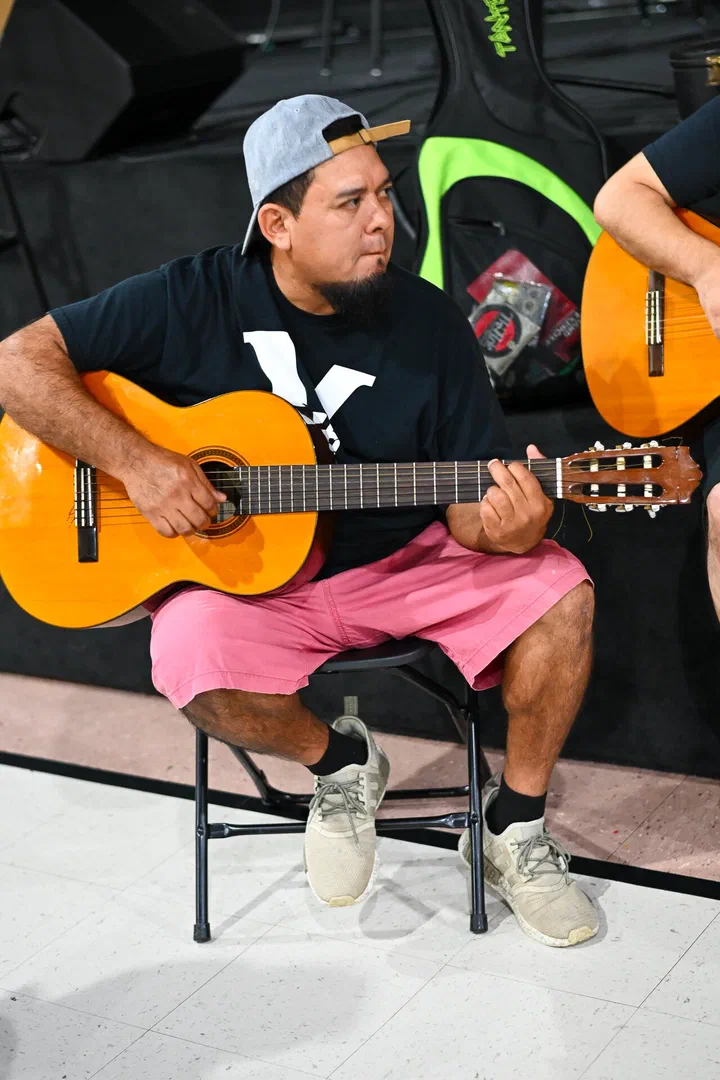 Germán tocando la guitarra en un banquito