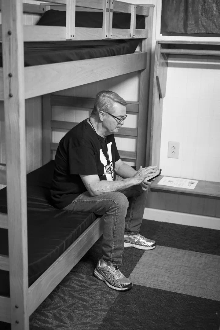 El pastor Rick Todd sentado en su litera mirando el teléfono