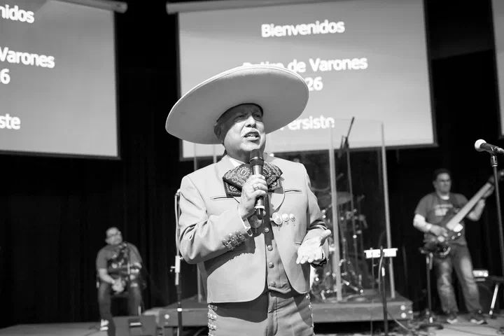 Cantante con traje de charro y sombrero, cantando en la tarima