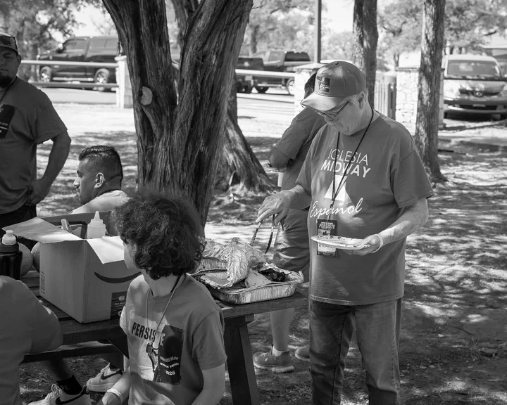 Hermanos compartiendo en las mesas bajo los árboles